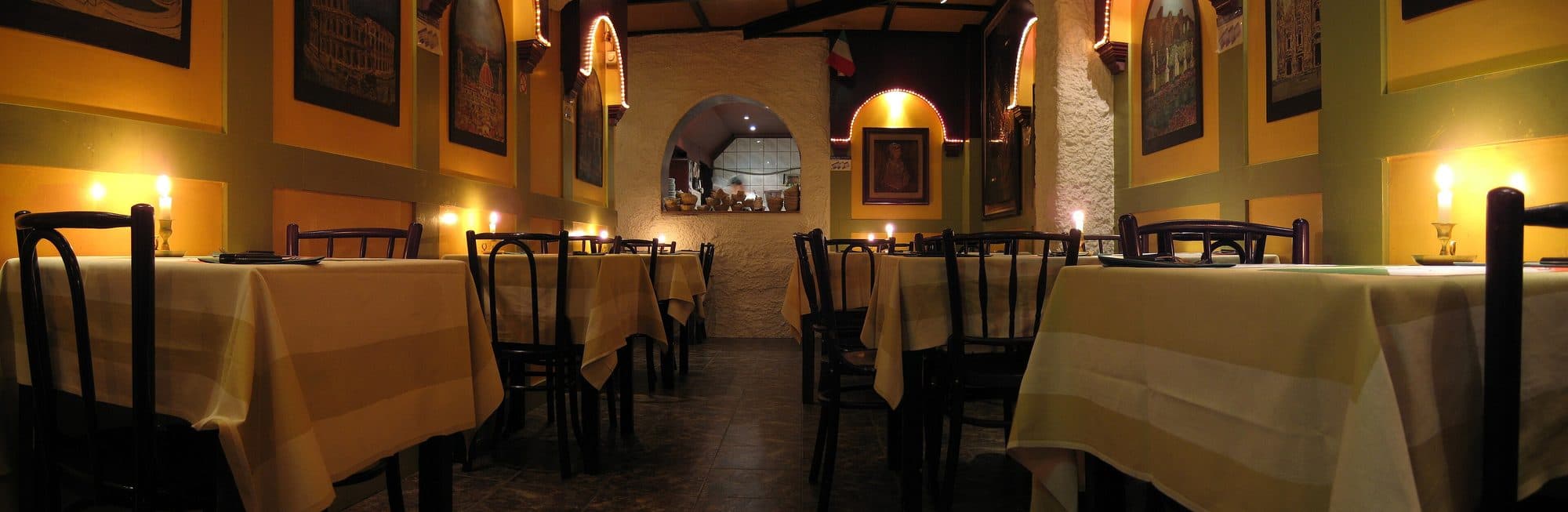 Salón de una pizzería con mesas puestas.